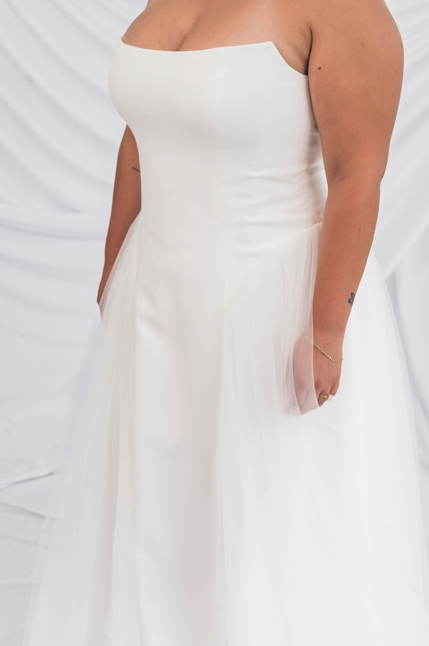 closeup of abigail gown, white strapless column gown with tulle hit detail. Cat eye neckline